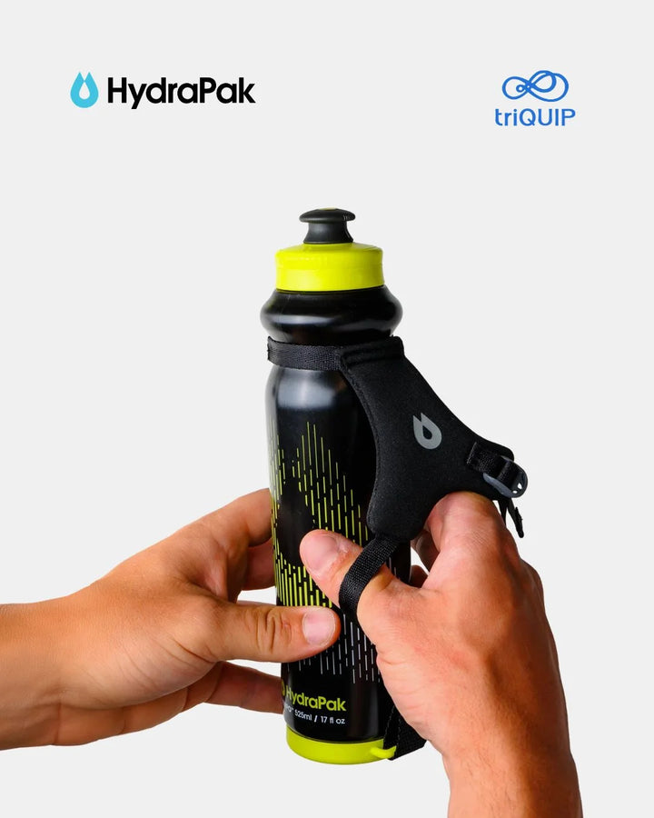 A person's hands holding a black and neon yellow HydraPak water bottle with a black wrist strap, shown against a light gray background with HydraPak and triQUIP logos at the top.